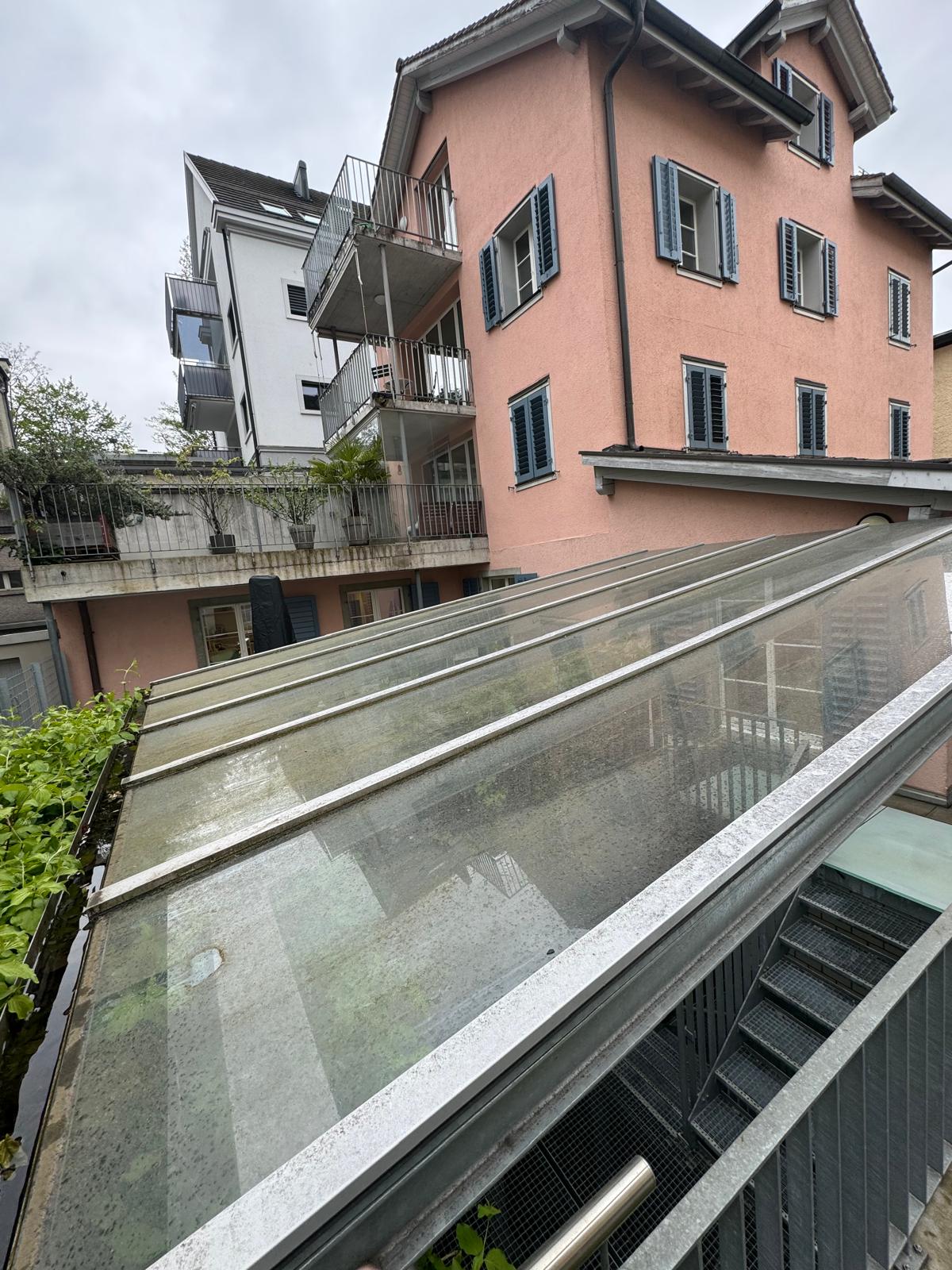 Gereinigtes Glasdach vor einem rosa Wohnhaus